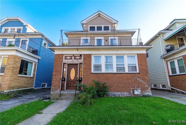 traditional style home featuring a balcony, a front yard, and brick siding