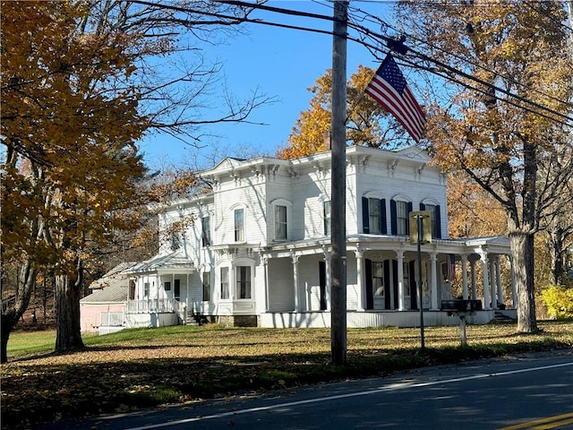 italianate-style house featuring a porch and a front yard