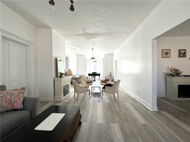 dining area featuring a notable chandelier, a fireplace, light wood-style flooring, and baseboards