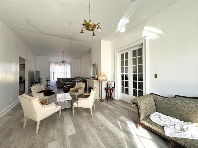 living area featuring light wood-type flooring, an inviting chandelier, and french doors