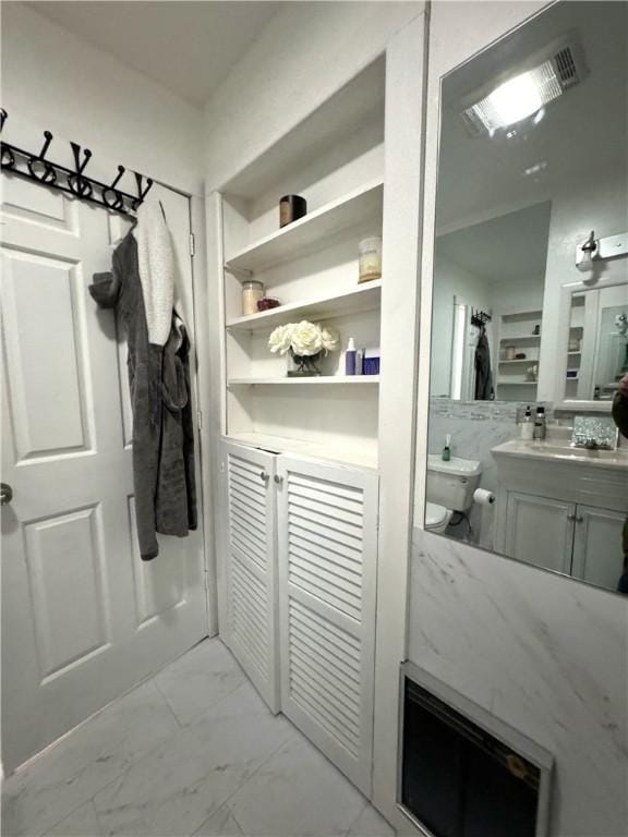 interior space with marble finish floor, vanity, and toilet