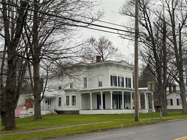 italianate home with a chimney, a porch, and a front yard