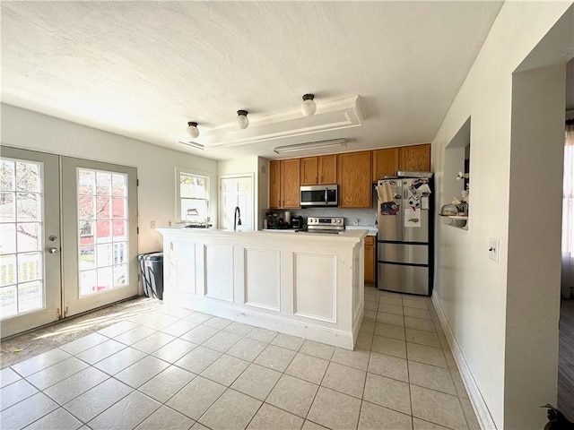 kitchen with a center island, brown cabinets, stainless steel appliances, light countertops, and a sink