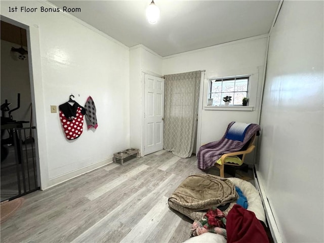 living area with light wood-type flooring and a baseboard heating unit