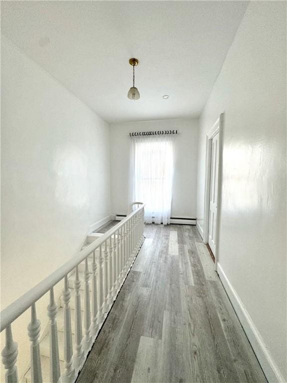 corridor with wood finished floors, an upstairs landing, and baseboards