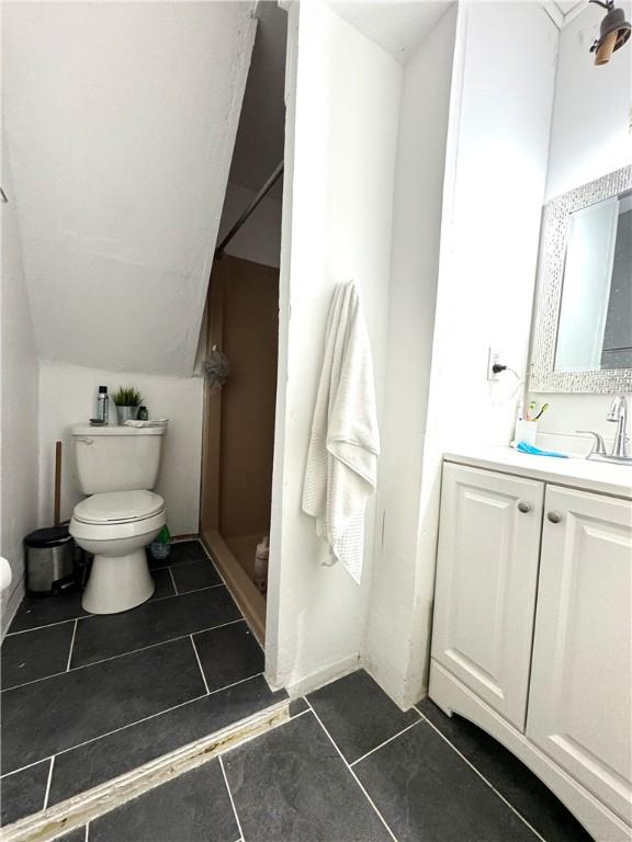 full bath with lofted ceiling, tile patterned flooring, a shower stall, and toilet