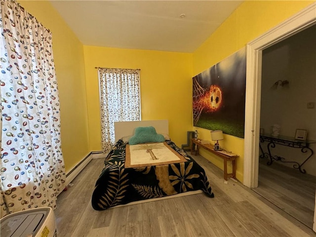 bedroom with baseboard heating, baseboards, and wood finished floors