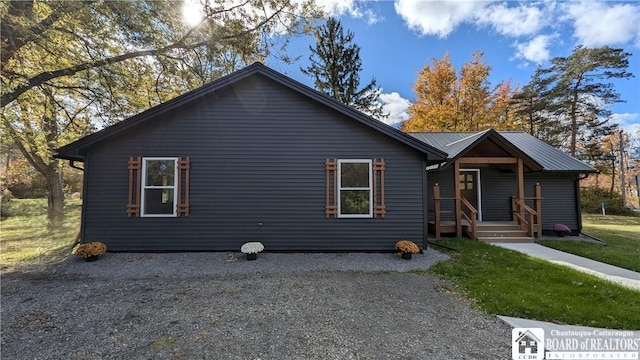 view of front of property with metal roof, driveway, and a front lawn