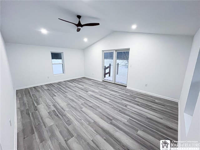 empty room featuring vaulted ceiling, wood finished floors, a ceiling fan, and baseboards