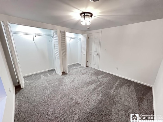 unfurnished bedroom with carpet flooring, baseboards, and two closets