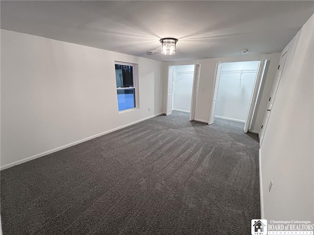 empty room with dark colored carpet and baseboards