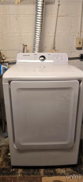 washroom featuring concrete block wall, washer / clothes dryer, and laundry area