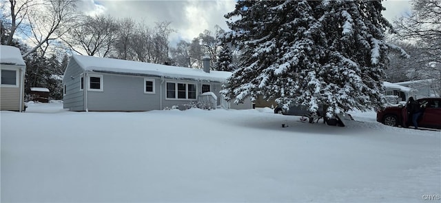 snow covered property with a garage and a chimney