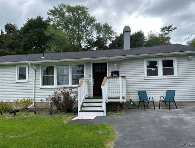 single story home with a front yard, a patio area, and a chimney