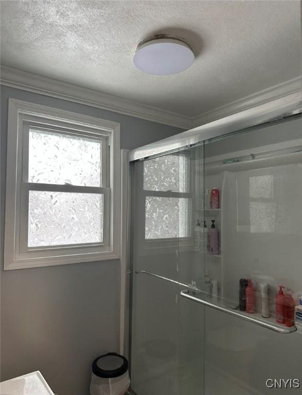 bathroom with ornamental molding, a stall shower, and a textured ceiling