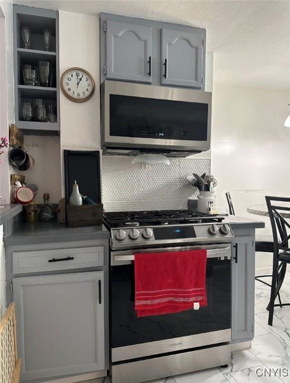 kitchen featuring marble finish floor, stainless steel appliances, tasteful backsplash, and gray cabinets