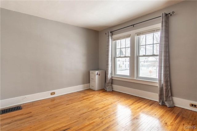 spare room featuring baseboards, visible vents, and light wood finished floors