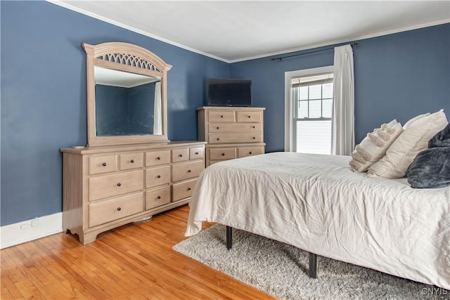 bedroom featuring light wood finished floors, baseboards, and crown molding