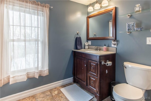 half bath featuring toilet, baseboards, a wealth of natural light, and vanity