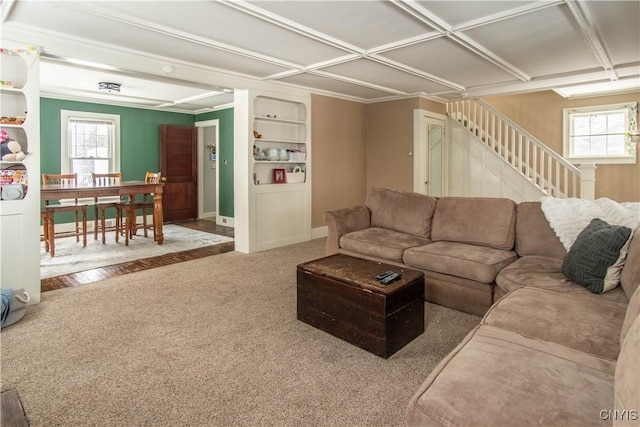 carpeted living area with stairway, built in features, and a healthy amount of sunlight