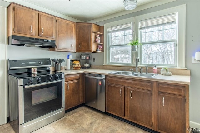 kitchen with light countertops, appliances with stainless steel finishes, a sink, and under cabinet range hood