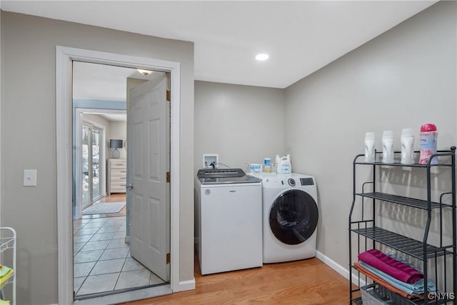 laundry room featuring washing machine and dryer, laundry area, light wood-style flooring, and baseboards