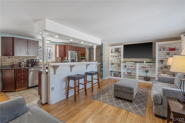 living area featuring decorative columns and light wood-style floors