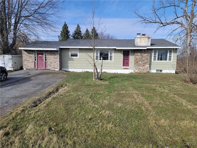 single story home featuring a chimney, aphalt driveway, and a front yard