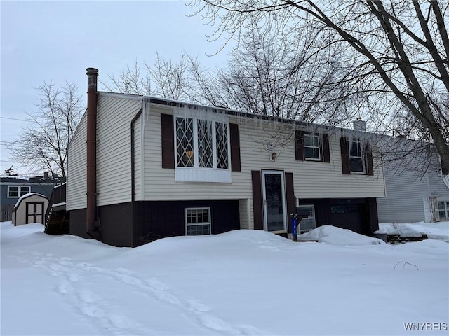 split foyer home with a chimney and a shed