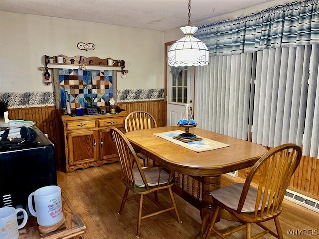 dining area with wood walls, wainscoting, wood finished floors, and visible vents