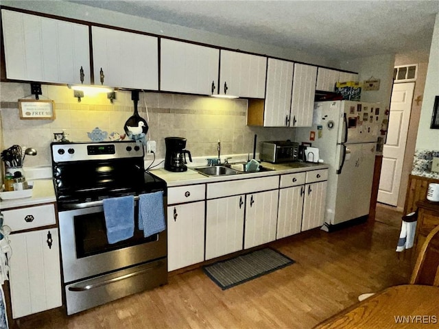 kitchen with light wood-style floors, stainless steel electric stove, light countertops, and a sink