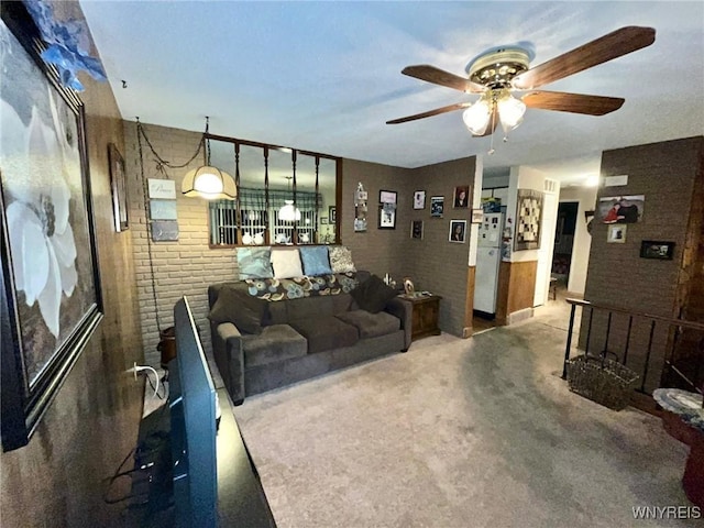 living area with a ceiling fan and brick wall