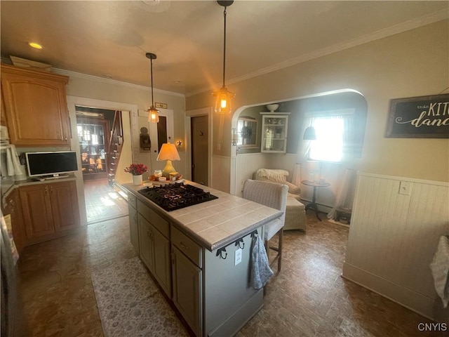 kitchen featuring arched walkways, tile counters, a center island, hanging light fixtures, and black gas cooktop