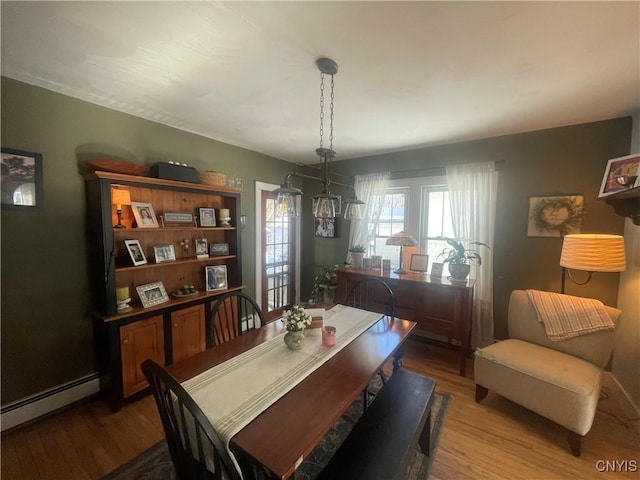 dining space featuring a baseboard radiator and wood finished floors