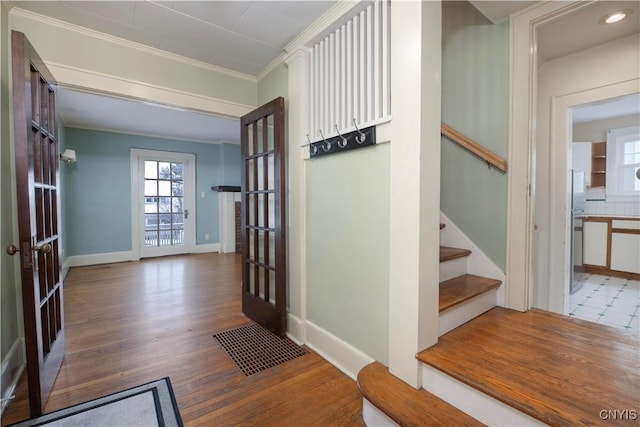 interior space featuring stairs, baseboards, wood finished floors, and crown molding