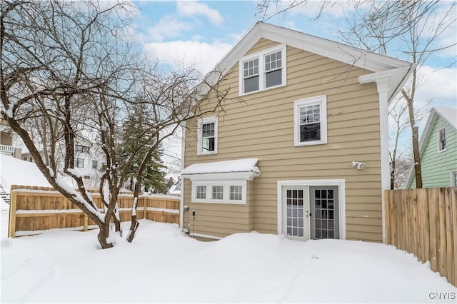 snow covered rear of property featuring a fenced backyard