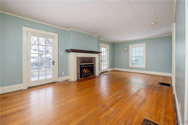 unfurnished living room with ornamental molding, light wood-type flooring, visible vents, and a fireplace