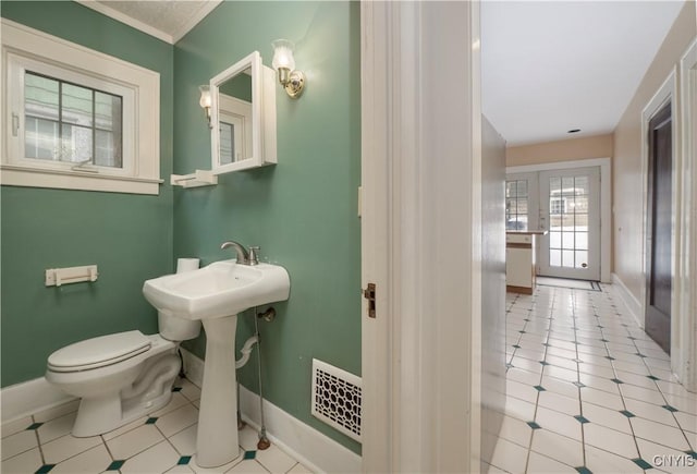 half bath featuring toilet, baseboards, visible vents, and tile patterned floors