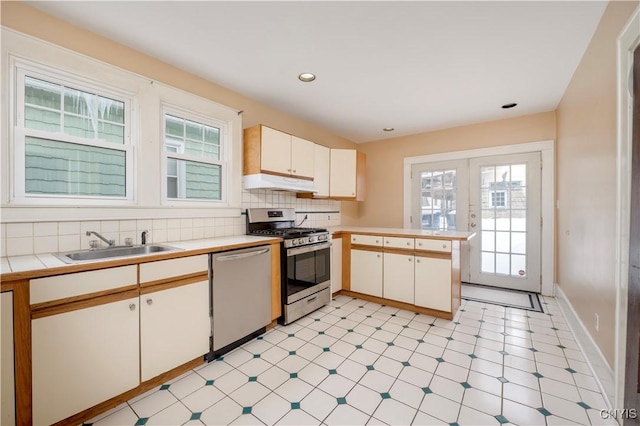 kitchen featuring appliances with stainless steel finishes, a peninsula, under cabinet range hood, light countertops, and light floors