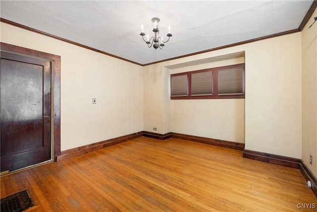 spare room with baseboards, visible vents, ornamental molding, light wood-style floors, and a notable chandelier