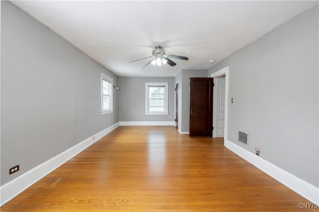 unfurnished room featuring a ceiling fan, light wood-type flooring, visible vents, and baseboards