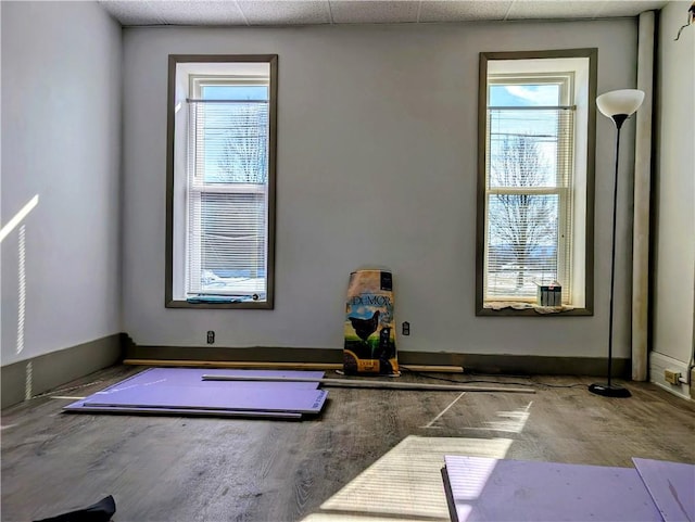 workout room featuring a drop ceiling and baseboards