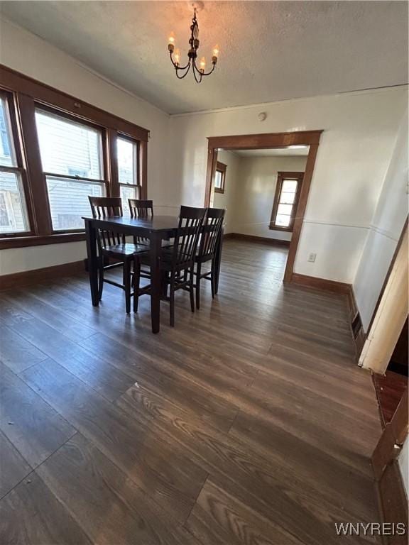 dining area featuring dark wood-style floors, a chandelier, a textured ceiling, and baseboards