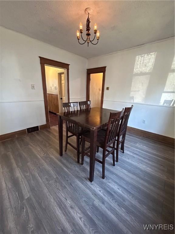 dining room with a chandelier, dark wood finished floors, and baseboards