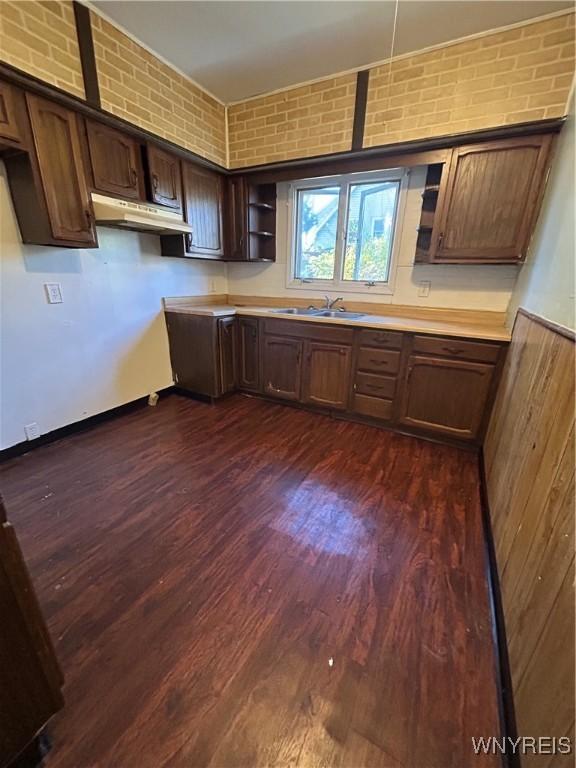 kitchen featuring under cabinet range hood, a sink, light countertops, dark brown cabinets, and dark wood finished floors