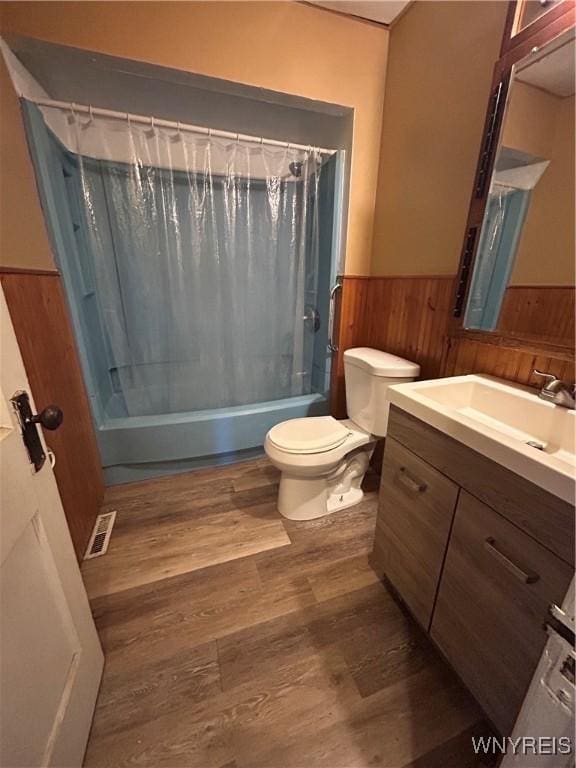 full bathroom featuring a wainscoted wall, wood finished floors, vanity, visible vents, and shower / bath combination with curtain