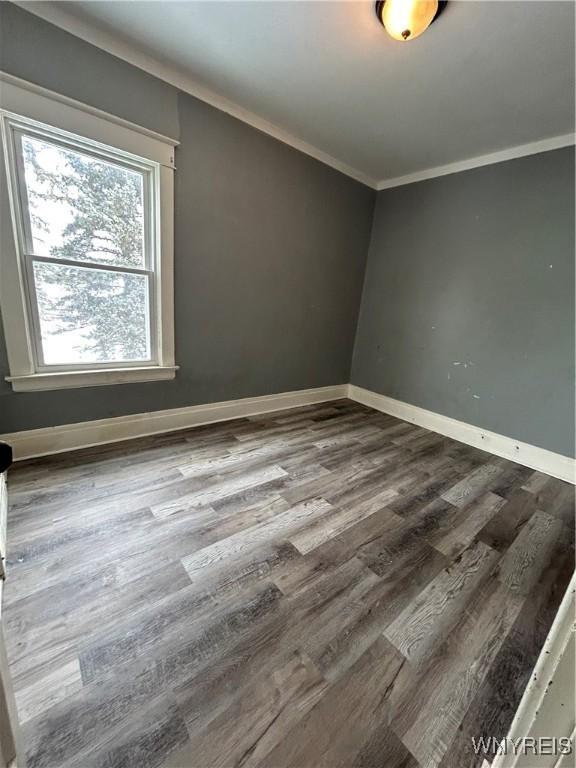 unfurnished room with crown molding, baseboards, and wood finished floors