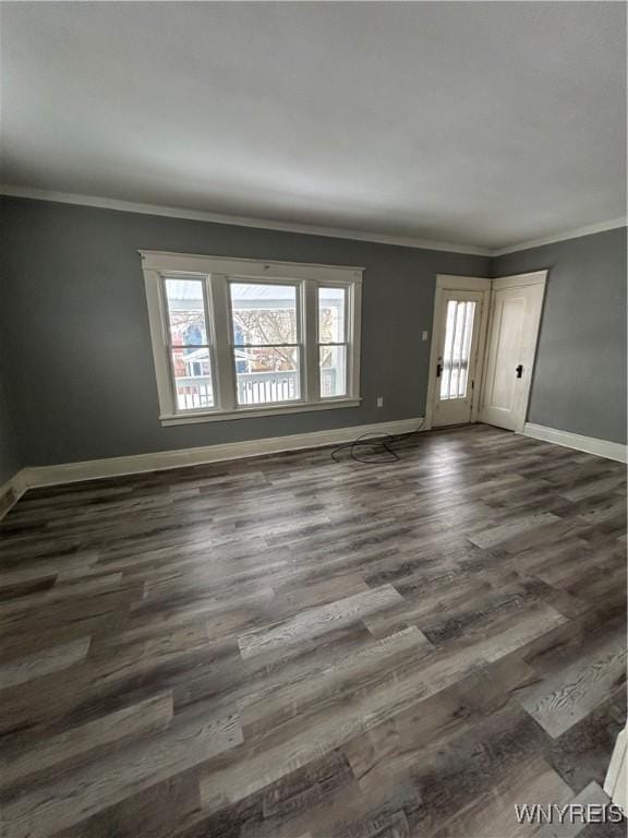 empty room with baseboards, ornamental molding, and dark wood-type flooring