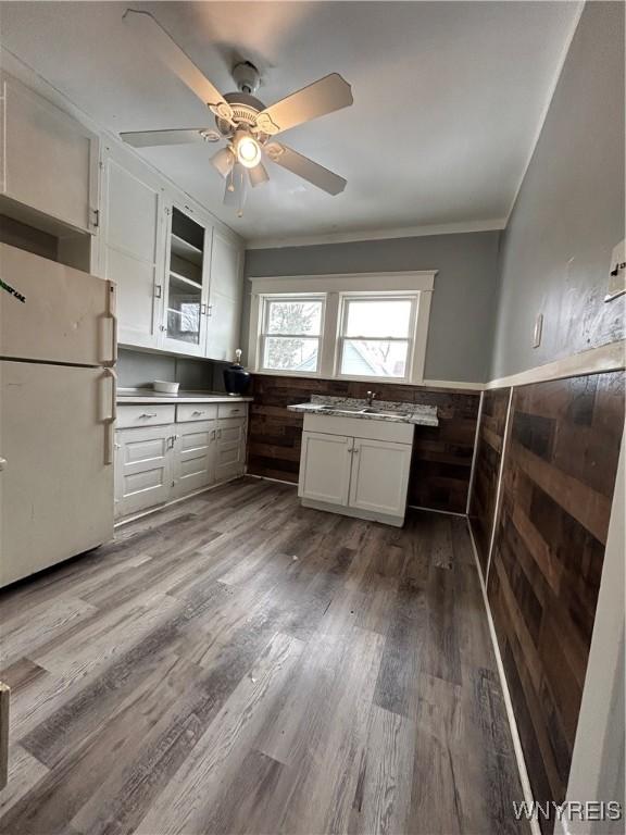 kitchen with wood finished floors, white cabinets, ornamental molding, wainscoting, and freestanding refrigerator