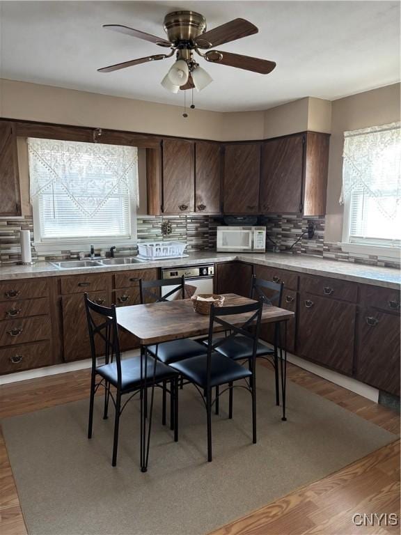 kitchen with light countertops, dark brown cabinets, a sink, and light wood-style floors